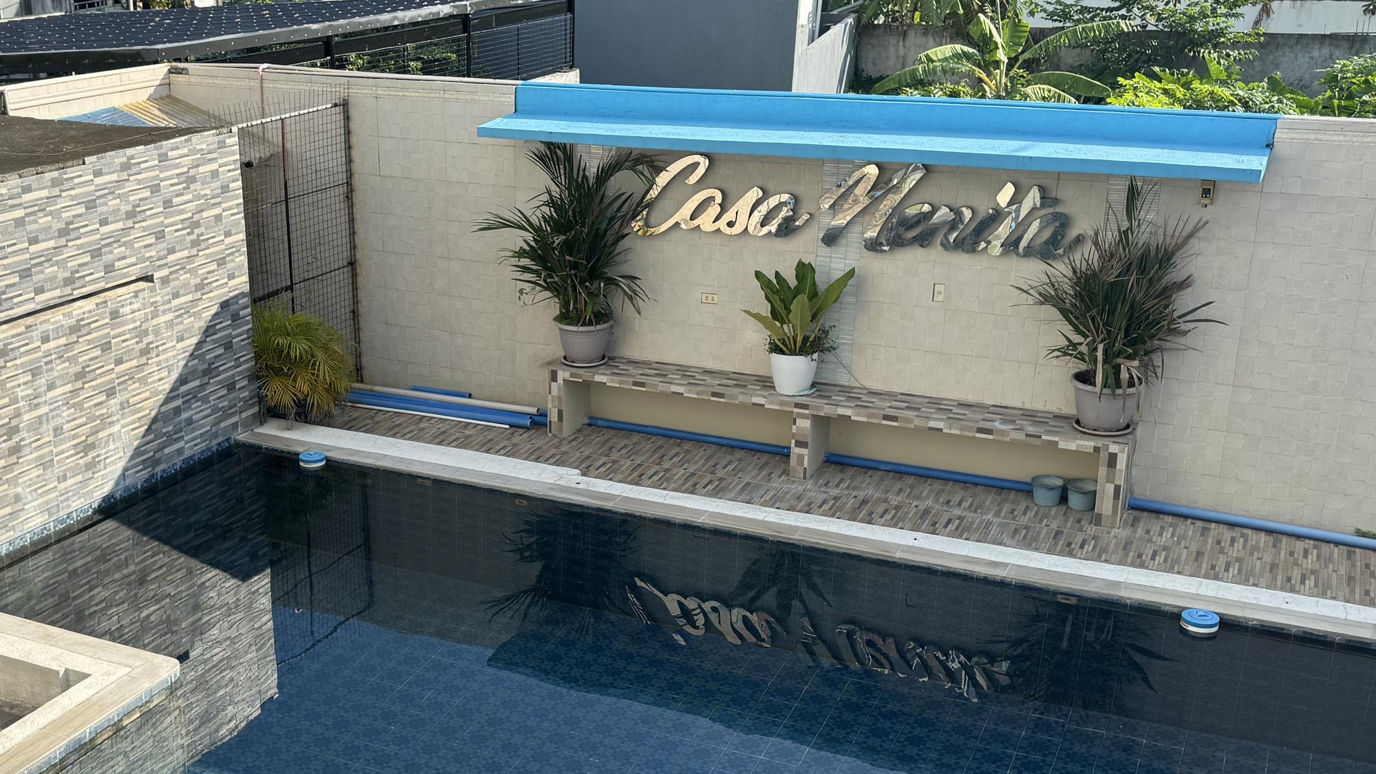 The swimming pool at Casa Nenita, with the resort's name on the wall behind it